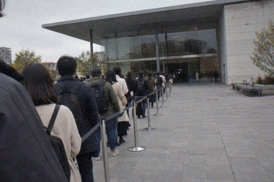 A museum entrance lobby with ticket machines and a queue barrier beside instant noodle exhibits