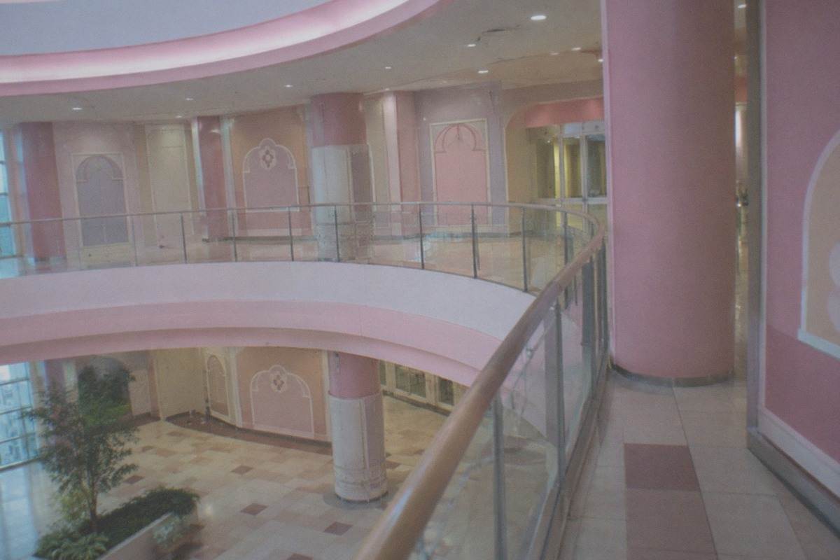 A colorful indoor theme park atrium decorated with pastel ribbons and a large decorated tree