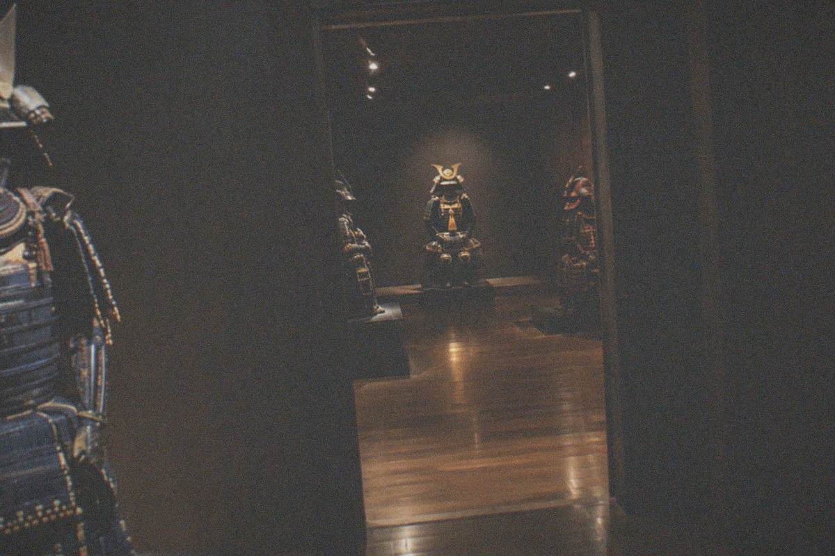 Samurai armour and helmets displayed in a dimly lit museum gallery with wooden beams
