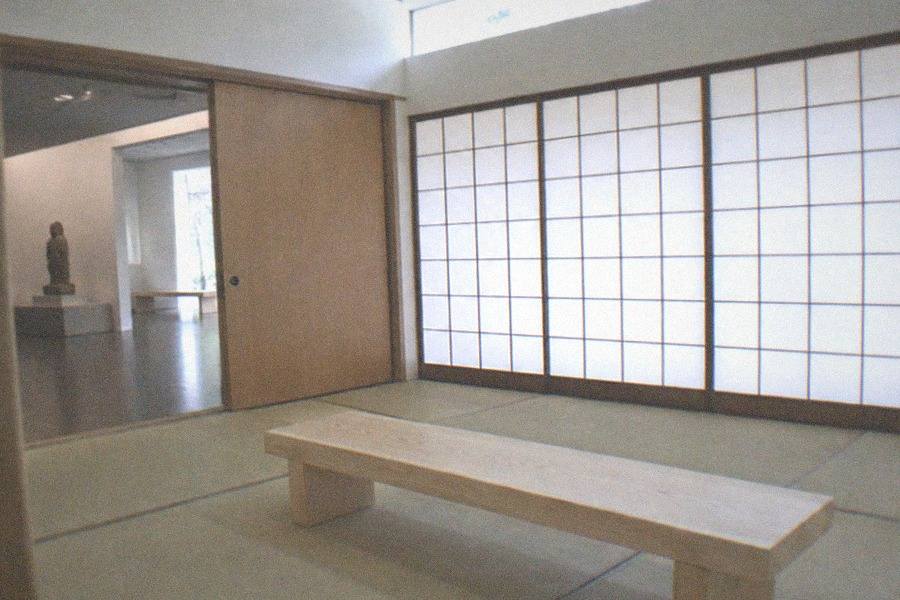 A museum ticket counter area with a short queue of visitors at a glass window