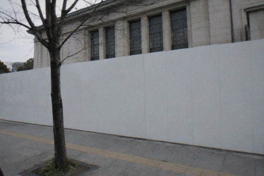 A shallow pool of water inside a dark exhibition space reflecting coloured lights