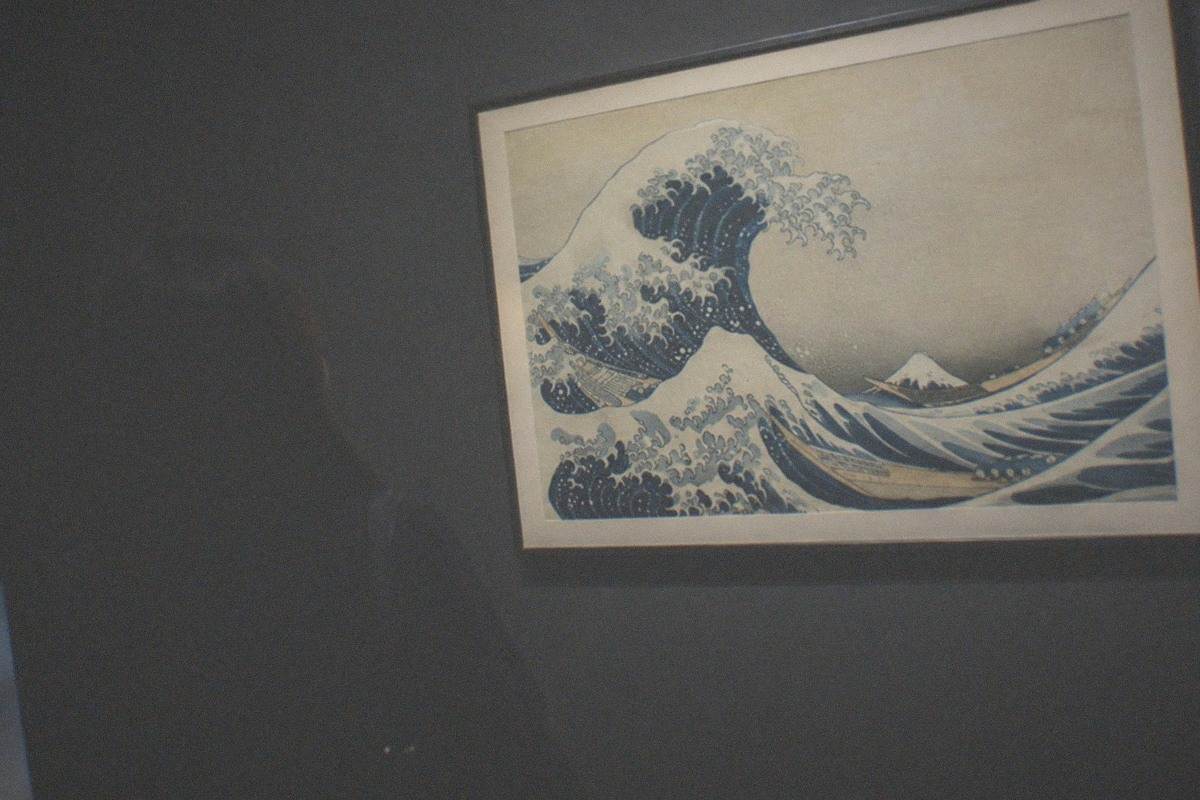 Woodblock print of a great wave curling over fishing boats with Mount Fuji in the distance