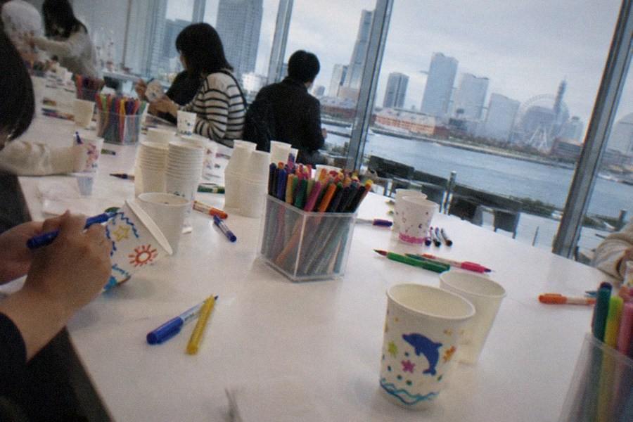 Visitors browsing the packaging wall at CUPNOODLES MUSEUM Yokohama, hundreds of instant noodle cups displayed in rows