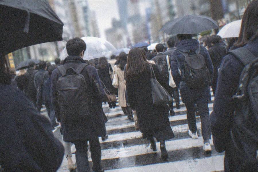 A railway station platform in Tokyo, commuters waiting beside a train at the edge