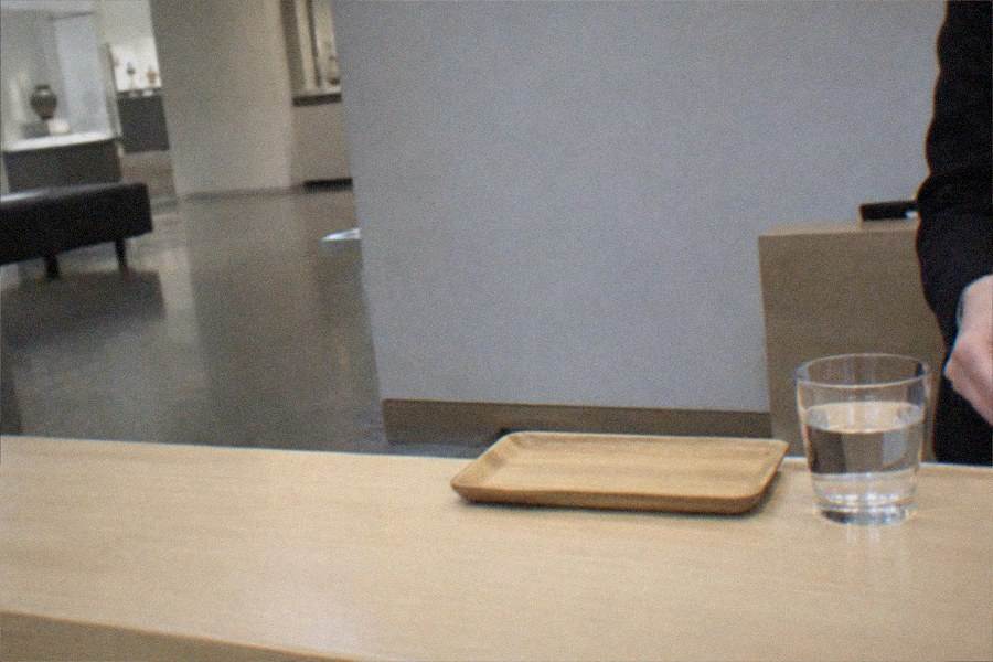Museum ticket counter with a staff member serving a visitor in a bright lobby