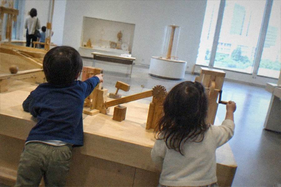 A family pointing at glowing interactive projections on a large gallery wall